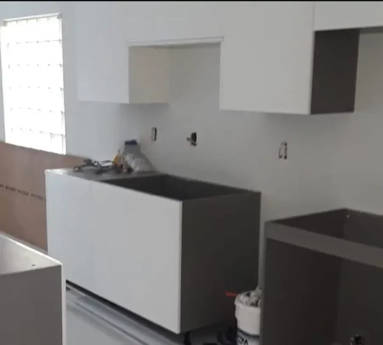 Kitchen cabinets during installation, with white upper cabinets and dark base cabinet frames