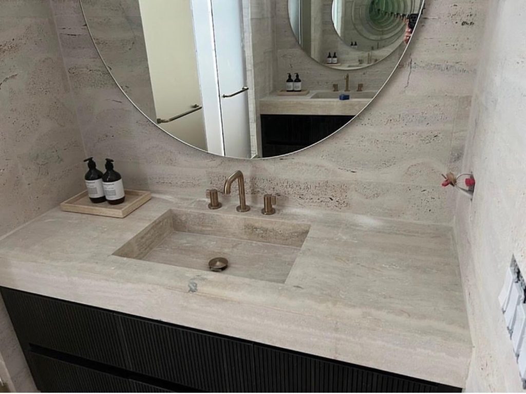Dark ribbed bathroom vanity with integrated stone sink and round mirror